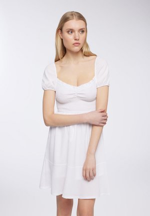 Abito bianco con maniche corte a sbuffo, corpetto testurizzato e gonna svasata. Presenta un scollo quadrato e dettagli arricciati sul davanti.