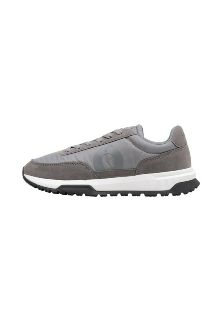 Zapatillas deportivas grises con una parte superior de textil suave, acentos de ante, una suela plana y un detalle de logo en el lateral. Diseño ligero y de bajo perfil.