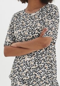 Top a maniche corte con motivo leopardato, in colori nero, beige e bianco. Realizzato in tessuto morbido con una vestibilità comoda.