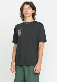Zwarte katoenen t-shirt met ronde hals, korte mouwen en een grafisch ontwerp op de linkerborst. Relaxed fit, gladde textuur.