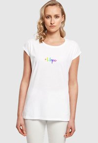 Hvit bomulls T-skjorte med rullede ermer, med en flerfarget "#Hope" tekstdesign på forsiden. Glatt tekstur, avslappet passform.