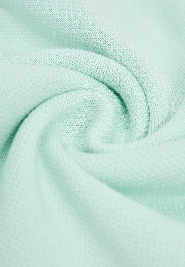 Helles mintgrünes Gewebe aus einem weichen Rippenstrick, das eine glatte Textur aufweist und eine gedrehte, spiralförmige Formation zeigt, die seine Flexibilität betont.