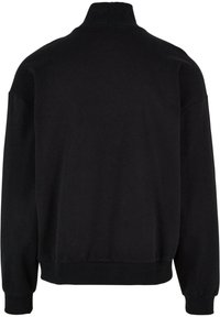 Sudadera negra de cuello alto, hecha de un material suave, con puños y dobladillo acanalados, y un corte relajado.
