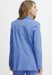 Jasnoniebieska marynarka wykonana z gładkiego, lekkiego materiału, z klasycznym kołnierzem, guzikami przy mankietach oraz dopasowanym, strukturalnym krojem.