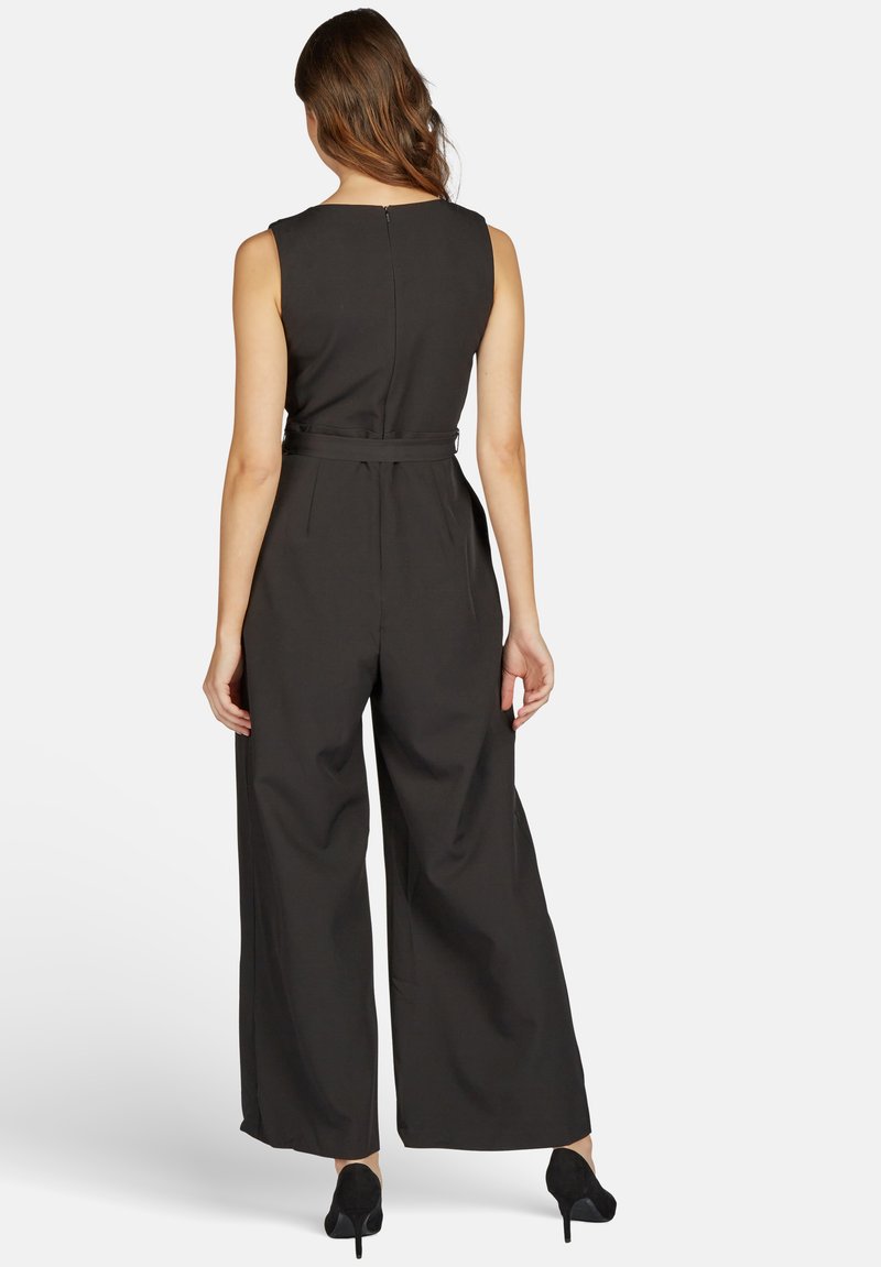 Schwarzer ärmelloser Jumpsuit mit weitem Bein, einem Taillengürtel und einem Reißverschluss auf der Rückseite. Der Stoff wirkt glatt und leicht strukturiert.