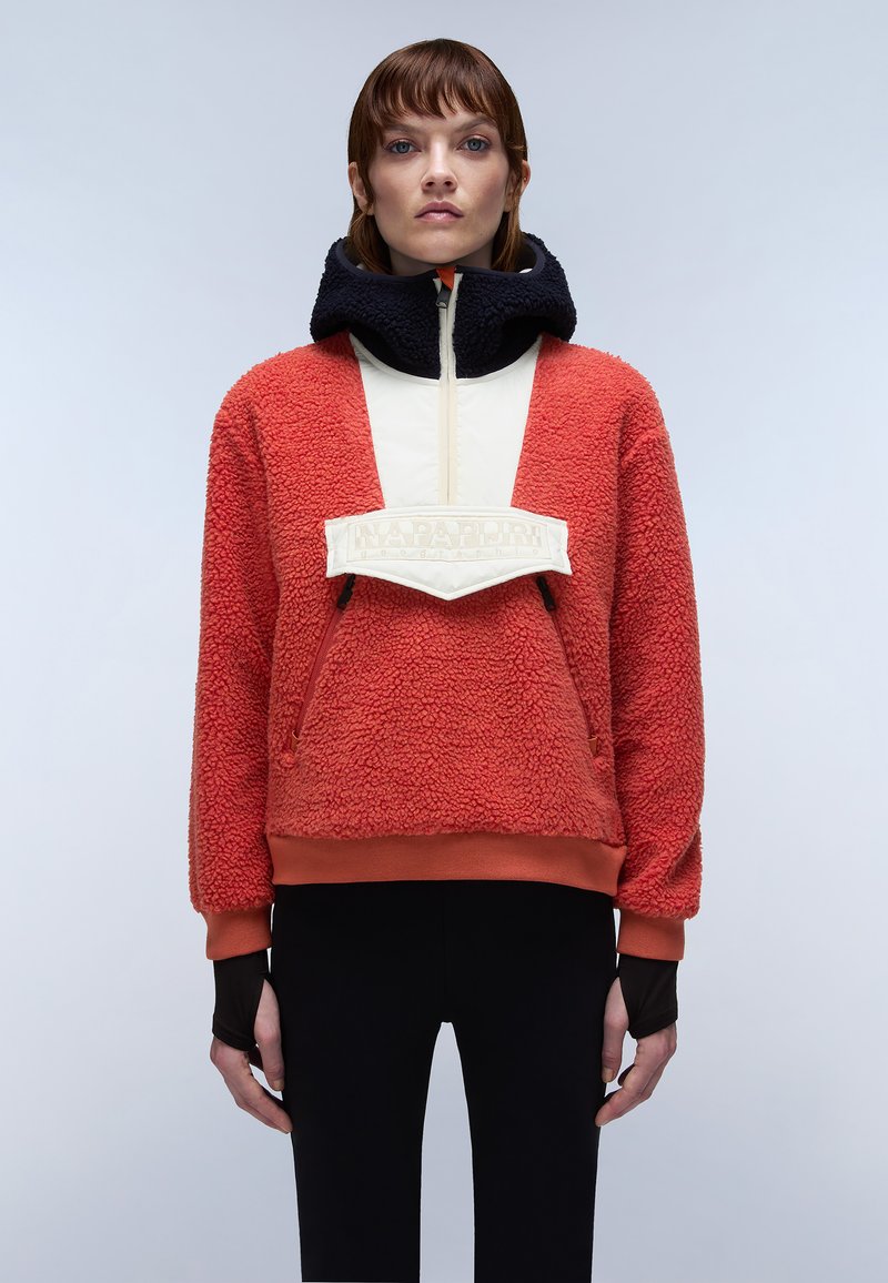 Rød fleece pullover med høj krave, kontrasterende cremefarvet frontpanel. Accenteret med et hvidt logo patch og sorte ærmer, med en afslappet pasform.