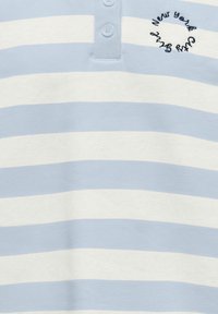 Modra s svetlo modrimi in belimi črtami polo majica iz bombaža. Ima trirazpotno zapenjanje z gumbi in vezen napis "New York" v krožnem vzorcu.