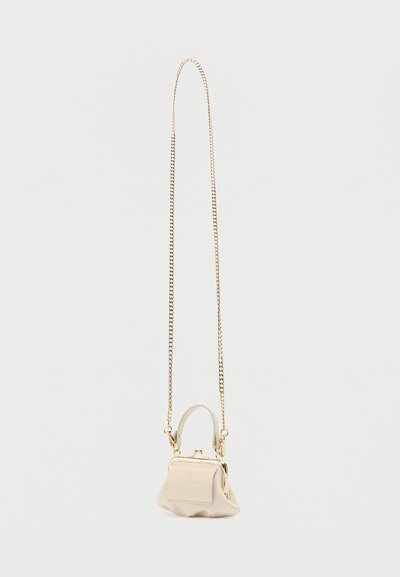 Μικρό μπεζ τσαντάκι με κοντή λαβή και μακρύ χρυσό αλυσίδα λουρί, παρουσιάζεται σε απλό λευκό φόντο.
