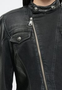 Must have musta must have kamuflaaž must be black mix of textured denim and smooth leather. Includes zip closure, snap buttons and chest pockets with decorative stitching.