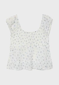 Blouse blanche sans manches avec petit imprimé floral bleu, corsage froncé, bretelles volantées et ourlet évasé avec volant.