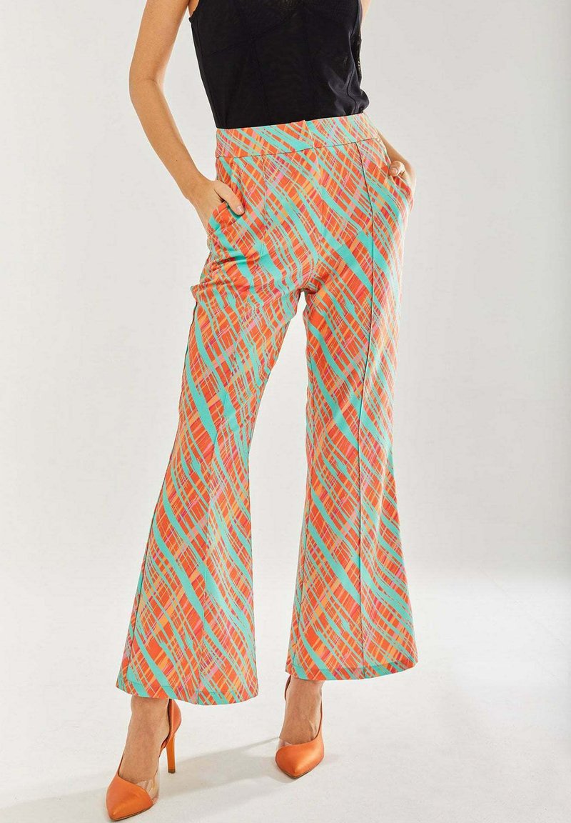 Colorful flared pants in vibrant orange, teal, and red plaid pattern. Elastic waistband and side pockets. Paired with orange heels.