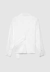 White long-sleeve shirt with a classic collar. Features a unique back design with a side tie. Smooth, woven fabric and buttoned cuffs.