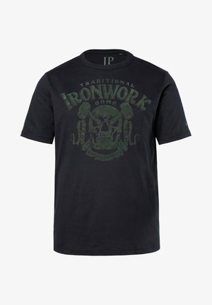 T-shirt nero a maniche corte in cotone, con una grafica di teschio verde e strumenti incrociati, accompagnata dal testo "Traditional Ironwork Comp."