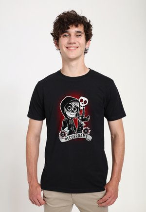 Black t-shirt featuring a graphic print of a skeletal character, dog, and flowers, with the text "RECUErdame" in a banner.