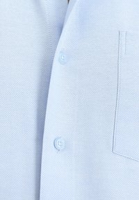 Camicia in tessuto testurizzato azzurro chiaro con placca dei bottoni e taschino applicato. Materiale morbido con un motivo a trama sottile.