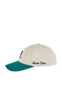 Casquette en coton beige avec une visière verte. Les caractéristiques incluent un texte brodé à l'avant et sur le côté, ainsi que six œillets de ventilation.