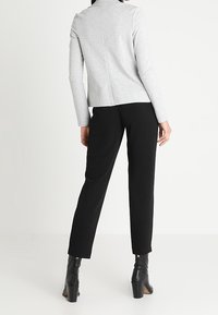 Šedý dlouhý rukáv s přiléhavým střihem a švem na zádech. Kombinováno s černými zúženými kalhotami a kotníkovými botami na širokém podpatku.