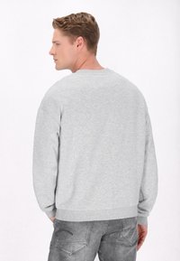 Lichtgrijze sweatshirt met ronde hals, gemaakt van een katoenmix, met ribgebreide manchetten en zoom. De achterkant toont een minimaal stikseldetail.