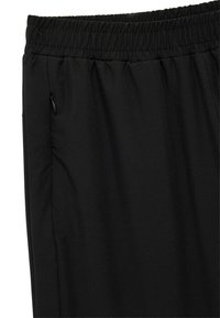 Pantalones deportivos negros con una pretina elástica, bolsillo lateral con cremallera y una textura de tela suave y ligera.