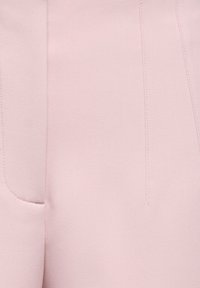 Minkštas rožinis audinys su matomomis vertikaliomis siūlėmis ir išgaubto siūlės detalė.