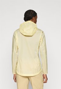 Ανοιχτό κίτρινο, ελαφρύ μπουφάν με κουκούλα, με διακριτική υφή, μακριά μανίκια και καμπυλωτή γραμμή στο πίσω μέρος.