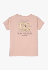 Růžové bavlněné tričko s krátkými rukávy, na přední straně s grafikou v žlutém a černém textu. Design zahrnuje hvězdy a vintage motiv.