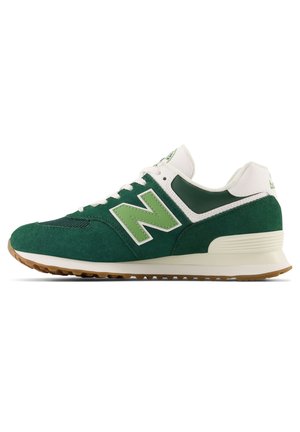 Niskie buty sportowe New Balance w kolorze zielonym i białym, z zamszową i siateczkową cholewką, jasną podeszwą i gumową podeszwą zewnętrzną, pokazane z profilu.