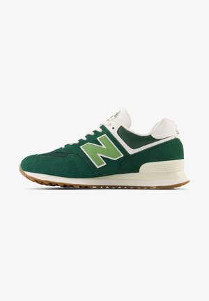 Niskie buty sportowe New Balance w kolorze zielonym i białym, z zamszową i siateczkową cholewką, jasną podeszwą i gumową podeszwą zewnętrzną, pokazane z profilu.