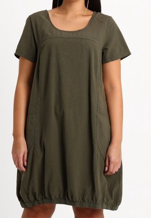Luźna sukienka w oliwkowej zieleni, z krótkimi rękawami, szerokim dekoltem i marszczonym dołem. Posiada boczne kieszenie oraz lekki materiał.