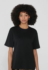 Czarny t-shirt wykonany z miękkiej tkaniny, o luźnym kroju, z krótkimi rękawami i okrągłym dekoltem. Prosty design bez widocznych wzorów czy akcentów.