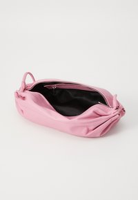 Rosa skinnveske med glidelås, teksturert overflate og rynket design; innsiden er svart stoff. Har et lite håndtak.