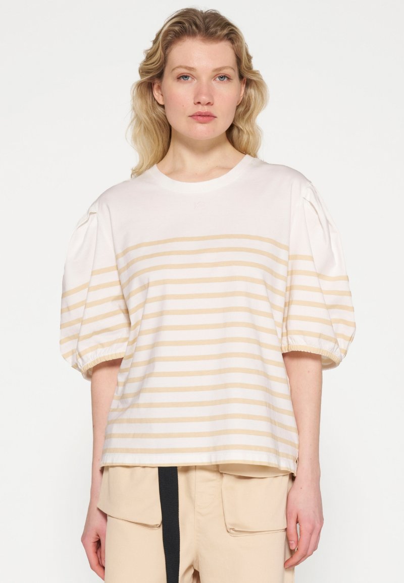 Camiseta de algodón a rayas con rayas horizontales en color beige claro y blanco, cuello redondo y mangas globo con puños fruncidos.