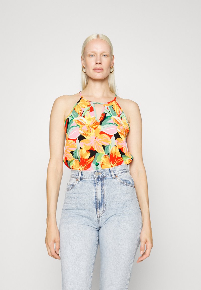 Top halter floral com um vibrante padrão de cores mistas, apresentando flores laranjas e cor-de-rosa sobre um fundo preto, combinado com jeans de cintura alta azul claro.