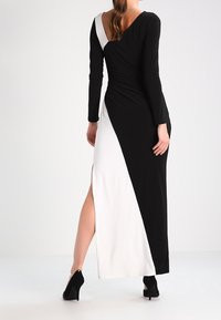 Lång klänning med svart och vitt färgblockdesign, med en sidslits, långa ärmar och V-halsringning bak. Gjord av mjukt tyg.