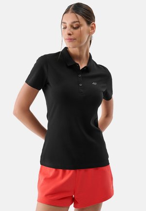 Czarna koszulka polo z kołnierzykiem i trzema guzikami, ozdobiona małym logo na piersi. Noszona z koralowymi szortami dla swobodnego wyglądu.