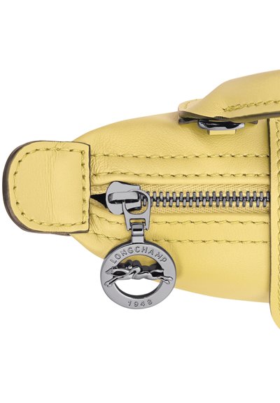 Yellow leather bag section with a silver zipper and circular Longchamp 1948 logo zipper pull. Visible stitching details.