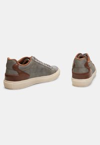Grijze suède sneakers met bruine leren accenten, platte rubberen zool, ronde neus en veters. Geweven panelen en contrasterende stiksels.
