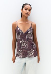 Purple, floral-patterned camisole with thin straps and a V-neck design. Soft texture with white and pink accents throughout the pattern.