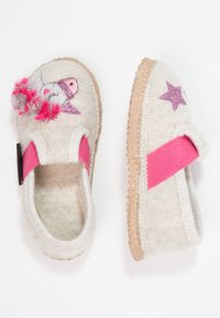 Chaussons en feutre gris clair avec une sangle élastique rose. Présentent une étoile pailletée et un design d'animal ludique agrémenté de pompons colorés.