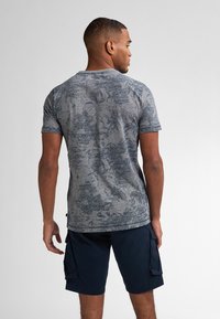 Tílko s krátkým rukávem, melírované šedé barvy se modrými vzory, spárované s tmavě modrými cargo šortkami s bočními kapsami a uvolněným střihem.