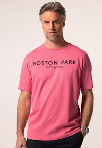 Růžové bavlněné tričko s krátkým rukávem a klasickým výstřihem. Na hrudi má nápis "BOSTON PARK EST 1996" tištěný v černé barvě.