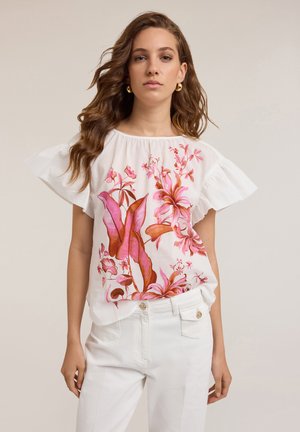 Witte blouse met geurende mouwen, versierd met levendige roze en oranje bloemenpatronen. Gecombineerd met een witte broek, wat een casual stijl laat zien.
