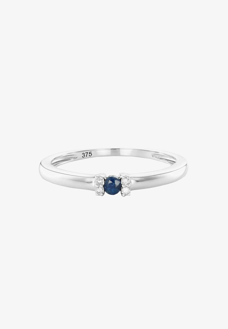 Bague en argent dotée d'une pierre précieuse bleue centrale flanquée de deux petites pierres claires, avec un anneau lisse et arrondi et un poinçon à l'intérieur.