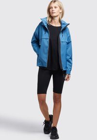 Blue waterproof jacket with a hood, front zipper, and two chest pockets, worn over a black shirt and black shorts; textured fabric.