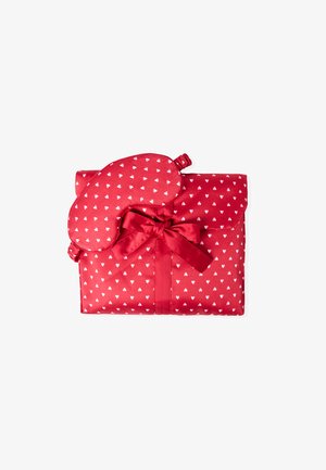 Conjunto de dormir de tela roja que incluye una máscara para dormir y una bolsa. Los materiales son satén suave con pequeños patrones de corazones blancos. Atado con un lazo a juego.