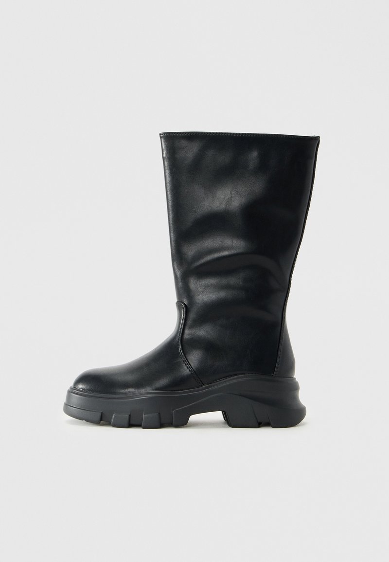 Botte noire en cuir mi-mollet avec semelle épaisse texturée et bout arrondi, vue de profil sur un fond gris clair uni.
