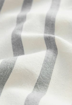 Ribakujuline kangas vahelduvate valgete ja heledate hallide triipudega, millel on sile tekstuur ja kudumispattern, näidates kortse ja rippuvust.