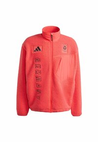 Fleecejacke in lebendigem Korallenrot mit durchgehendem Reißverschluss, hohem Kragen und schwarzen Akzenten. Mit "GERMANY" Schriftzug und einer Brusttasche.