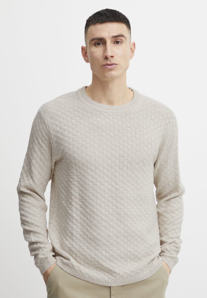 Beige knitted sweater featuring a textured pattern, round neckline, and long sleeves. Soft material with ribbed cuffs and hem.