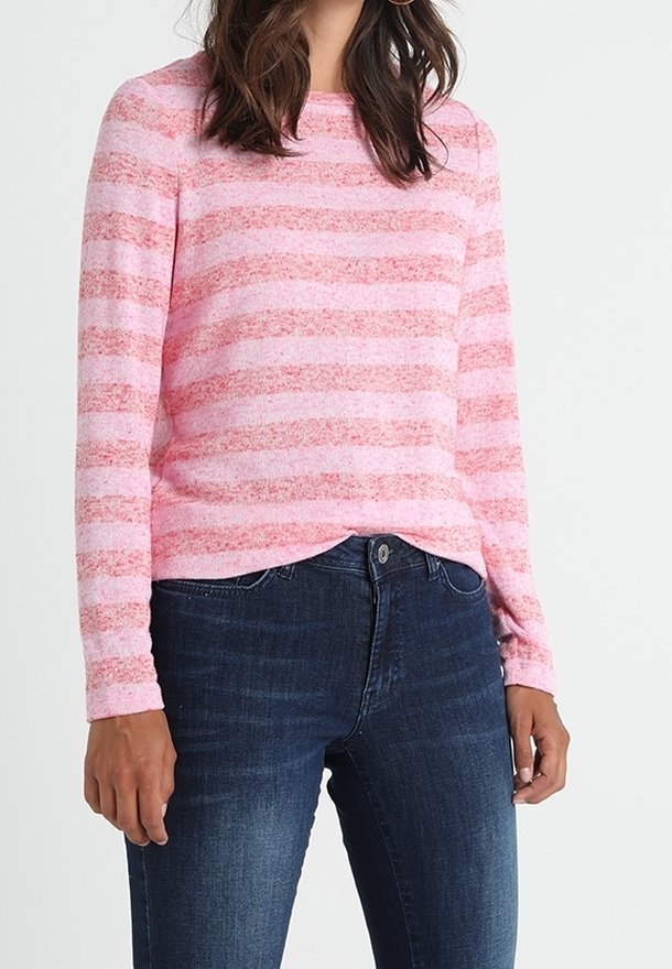 Ein rosa und weiß gestreifter Pullover aus weichem Strickmaterial mit Rundhalsausschnitt und langen Ärmeln, kombiniert mit dunkelblauen Jeans.